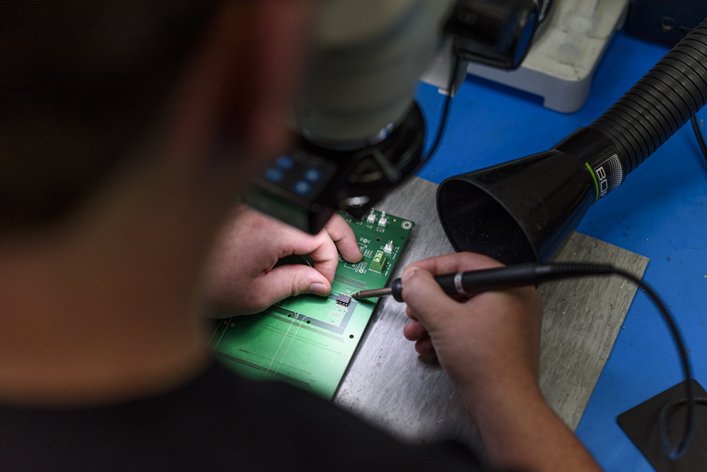 An electrical engineer soldering onto a circuit board